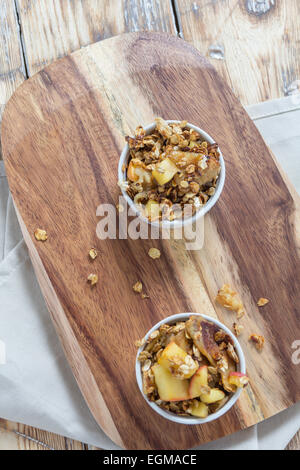 Deux bols de crumble aux pommes sur une planche en bois sur une table rustique Banque D'Images