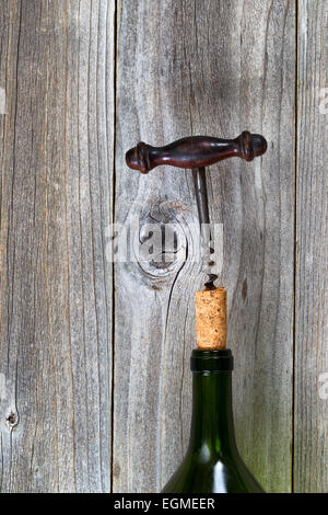 Vertical image d'antique corkscrew cork en tirant sur la bouteille de vin en bois rustique. Banque D'Images