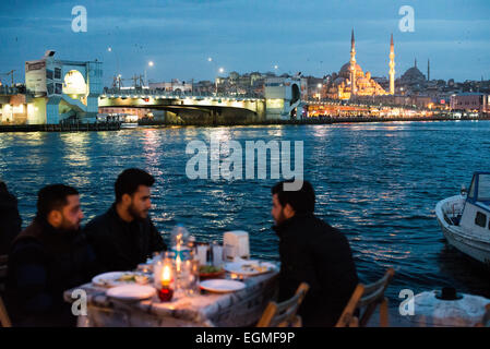 Restaurants du front de mer de la Corne d'Or Istanbul // ISTANBUL, Turquie — les convives apprécient les repas dans les restaurants en plein air le long du front de mer de la Corne d'Or à Karakoy, Istanbul. La Nouvelle Mosquée historique (Yeni Cami), achevée en 1665, et le pont de Galata offrent une toile de fond spectaculaire. Ces restaurants populaires en bord de mer proposent des fruits de mer frais et une cuisine turque traditionnelle avec vue sur les gratte-ciel historiques d'Istanbul. Banque D'Images