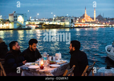 Dîner en plein air Nouvelle Mosquée Corne d'Or Pont de Galata Istanbul // ISTANBUL, Turquie — les convives mangent dans des restaurants extérieurs popup sur les rives de la Corne d'Or à Karakoy, avec le Pont de Galata et la Nouvelle Mosquée en arrière-plan. Banque D'Images
