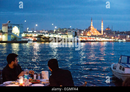 Restaurants en plein air de la Corne d'Or Istanbul Turquie // ISTANBUL, Turquie — les convives mangent dans des restaurants en plein air sur les rives de la Corne d'Or à Karakoy, avec le pont de Galata et la Nouvelle Mosquée en arrière-plan. Banque D'Images