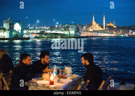 Restaurants en plein air de la Corne d'Or Istanbul Turquie // ISTANBUL, Turquie — les convives mangent dans des restaurants en plein air sur les rives de la Corne d'Or à Karakoy, avec le pont de Galata et la Nouvelle Mosquée en arrière-plan. Banque D'Images