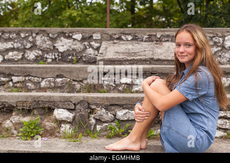 Jeune fille assise sur les marches de pierre à l'ancien parc de la ville. Banque D'Images