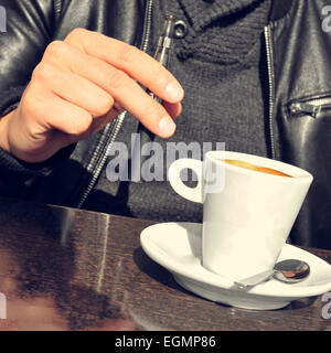 Libre d'un jeune homme avec une cigarette électronique et une tasse de café à la terrasse d'un café Banque D'Images