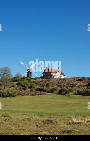 Un ciel bleu avec un moulin à vent anticyclonique, l'ajonc (Ulex europaeus) et Heather (Calluna Vulgaris) dans le soleil d'hiver à Reigate Heath Banque D'Images