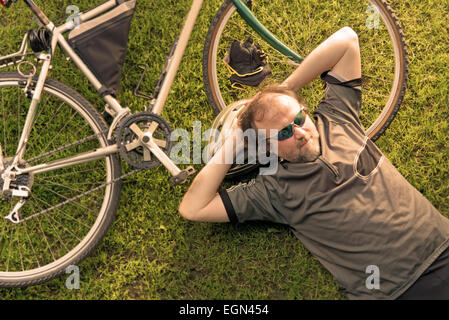 Biker couchage avec vélo dans la pelouse Banque D'Images