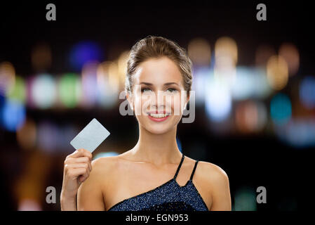 Smiling woman in evening dress holding credit card Banque D'Images