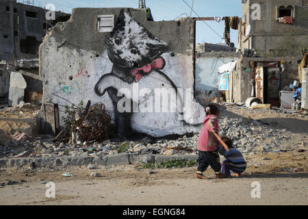 Les enfants palestiniens en face d'une peinture murale d'un chaton, dit avoir été peint par l'artiste de rue britannique Banksy, sur les vestiges d'une maison qui a été détruit pendant la guerre de 50 jours entre Israël et le Hamas militants dans l'été de 2014, dans la bande de Gaza ville de Beit Hanun. © Ahmed Hjazy/Pacific Press/Alamy Live News Banque D'Images