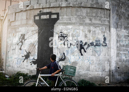 Les enfants palestiniens en face d'une peinture murale d'un chaton, dit avoir été peint par l'artiste de rue britannique Banksy, sur les vestiges d'une maison qui a été détruit pendant la guerre de 50 jours entre Israël et le Hamas militants dans l'été de 2014, dans la bande de Gaza ville de Beit Hanun. © Ahmed Hjazy/Pacific Press/Alamy Live News Banque D'Images