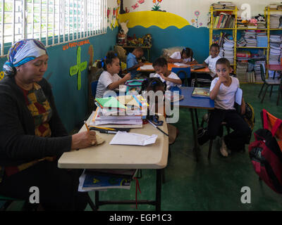 Professeur à l'école primaire en classe Puerto Plata République Dominicaine se concentrer sur leurs leçons malgré visite touristique interruption Banque D'Images