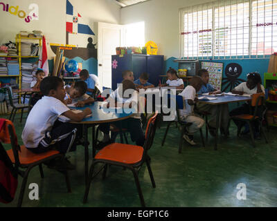 Les enfants de l'école primaire en classe Puerto Plata République Dominicaine se concentrer sur leurs leçons, malgré la visite d'un groupe de touristes Banque D'Images