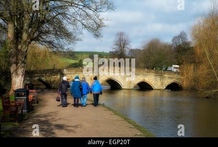 Personnes âgées Personnes âgées de marcher le long de la rivière Wye de bakewell avec le pont du 13ème siècle dans l'arrière-plan le Derbyshire, Angleterre Banque D'Images