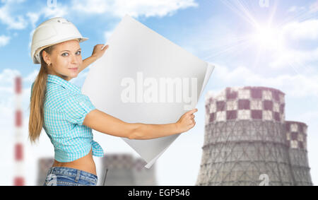 Woman in helmet holding feuille de papier. Regarde la caméra, sourit. Cheminées en toile Banque D'Images