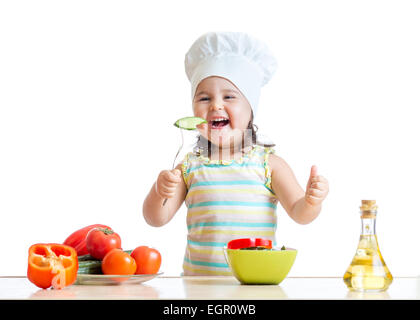 Fille enfant dans cook hat manger des légumes Banque D'Images