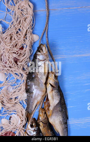 Le poisson séché avec filet de pêche sur fond bleu, vertical Banque D'Images