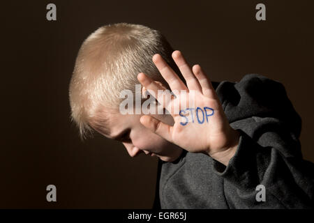 Contrarié d'abus peur petit enfant (garçon), arrêt main jesture close up portrait sombre horizontale with copy space Banque D'Images