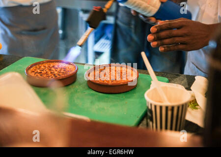 Afrocaribbean chef making crem brûlée avec un chalumeau Banque D'Images