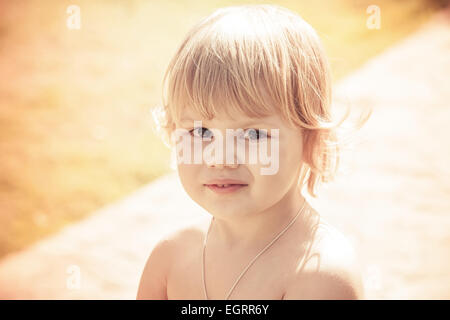 Piscine close-up portrait of cute smiling Caucasian baby girl blonde. Vintage photo aux tons orange avec effet de filtre de tonalité Banque D'Images