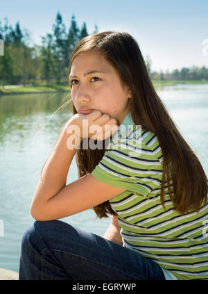 Vietnamienne/Caucasian girl se trouve à l'extérieur pensant reflétant la méditation de 11 à 13 ans .MR © Myrleen Pearson Banque D'Images