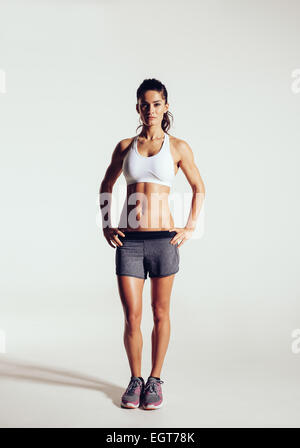 Jeune femme avec de beaux corps sain slim posing in studio. Modèle féminin en Fitness Sportswear sur fond gris Banque D'Images