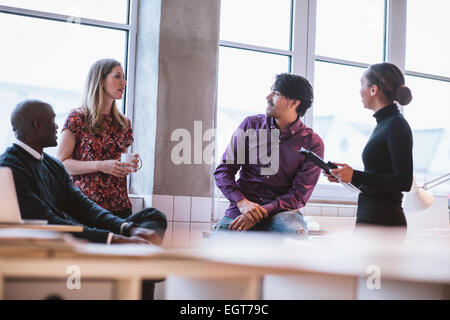 Les jeunes professionnels de l'équipe avoir discussion occasionnels en fonction. Les cadres supérieurs ayant friendly discussion pendant les pauses. Banque D'Images