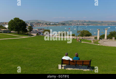 Couple enjoying view de la ville et la baie de Swanage Dorset England UK d'assise en bois côte sud près de Poole et Bournemouth en été Banque D'Images