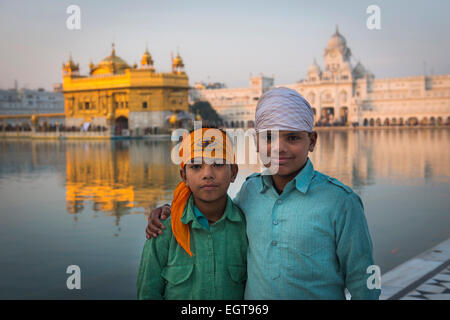 Deux jeunes garçons posent pour une photo devant le Temple d'Or, l'Amritsar au crépuscule. Banque D'Images