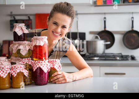 Portrait de jeune femme au foyer à partir de pots de confiture de fruits faits maison et légumes marinés Banque D'Images