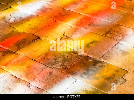 Lumières colorées sur le sol à cause de ce que le soleil brille à travers une fenêtre rouge et jaune. Banque D'Images