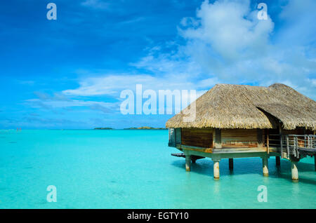Toit de chaume de luxe bungalow lune de miel dans un centre de vacances dans le bleu lagon de l'île tropicale de Bora Bora. Banque D'Images