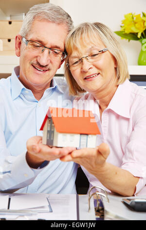 Happy senior couple holding a small house sur leurs mains Banque D'Images