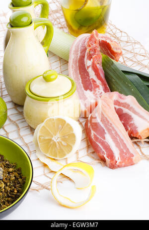 Les tranches de bacon avec du citron et herbes de pore sur tableau blanc Banque D'Images