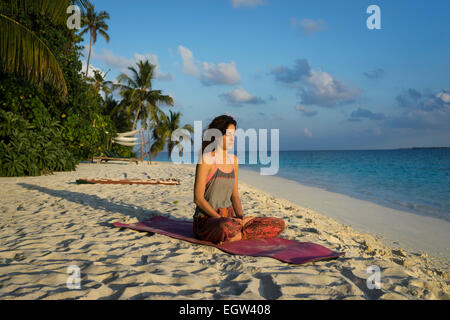 Woman meditating on beach dans les Maldives. Banque D'Images