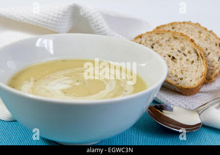 Soupe de Poireaux et pommes de terre fait maison dans un bol avec du pain frais sur le côté et agiter de crème sur le dessus Banque D'Images