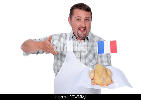 L'homme dans un tablier blanc offrant un tout poulet Français Banque D'Images
