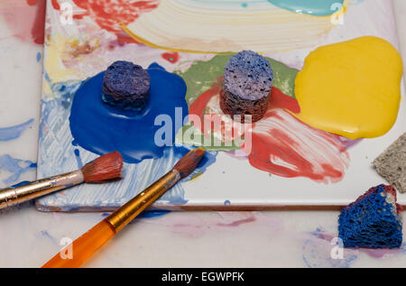 Pinceau éponge et peintures d'artistes sur une tuile utilisée comme une palette de peinture Banque D'Images