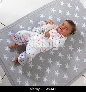 Bébé fille (7 mois) lying on blanket holding a soft toy Banque D'Images