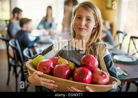 Une jeune fille portant un panier de pommes. Banque D'Images