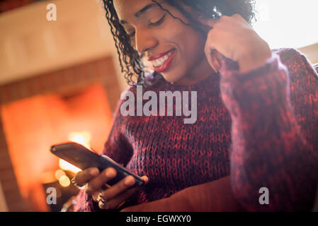 Une femme contrôler son téléphone portable et souriant. Banque D'Images