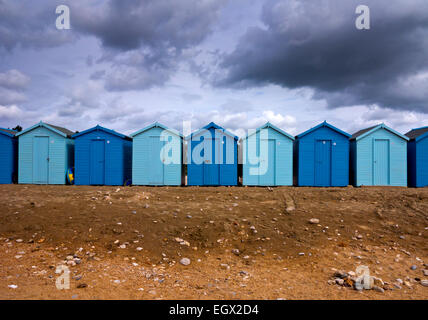 En bois peint bleu traditionnel des cabines de plage sous ciel d'orage à Charmouth sur la côte jurassique du Dorset south west England UK Banque D'Images