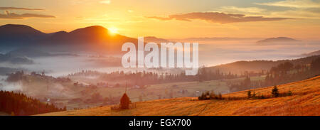 Lever du soleil, village de montagne dans le brouillard et tout gentil en voyant jaune Banque D'Images