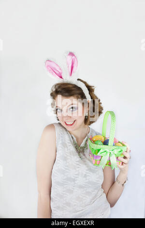 Belle jeune femme portant des oreilles de lapin et holding Easter basket avec des oeufs de Pâques. Banque D'Images