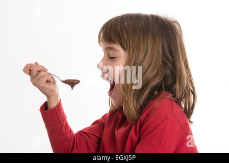 Petite fille manger une crème au chocolat isolé sur fond blanc Banque D'Images