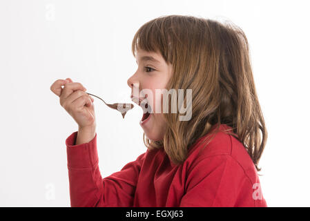 Petite fille manger une crème au chocolat isolé sur fond blanc Banque D'Images