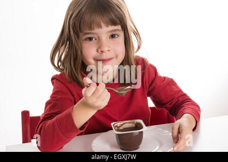 Petite fille manger une crème au chocolat isolé sur fond blanc Banque D'Images