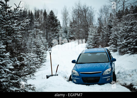 Voiture prise dans la neige sur une route forestière au milieu de nulle part. Banque D'Images