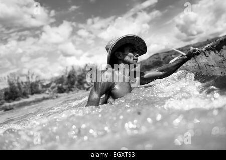 Un mineur de sable se soulève dans un seau rempli de sable tout en travaillant dans le milieu de la rivière La Vieja à Cartago, Colombie. Banque D'Images