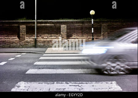 Voiture roulant sur un passage piéton dans la nuit Banque D'Images