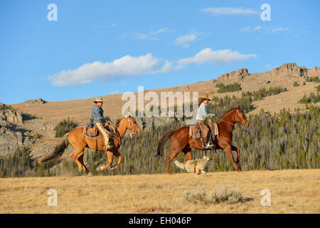 USA, Wyoming, deux cowgirls équitation et son chien courir Banque D'Images