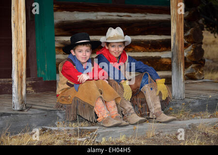 USA, Wyoming, deux jeunes cow-boys assis côte à côte Banque D'Images